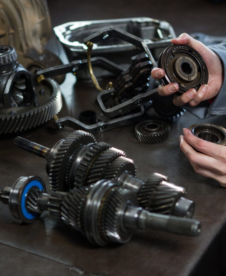 Close-up of female mechanic holding spare parts of car at repair garage